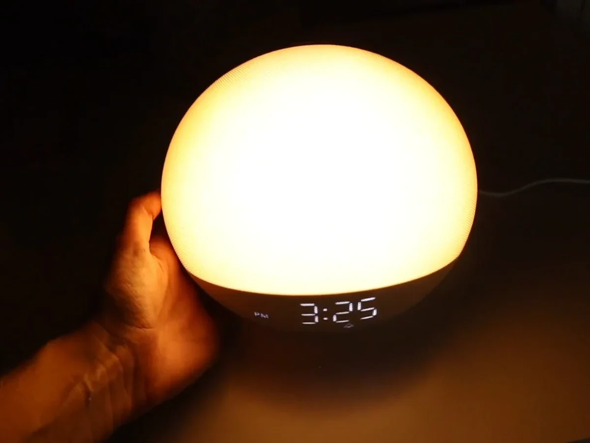 Exact Odokee H03 Putty sunrise alarm clock held beside its warm wake light display